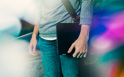 Man with shoulderbag and laptop in hand